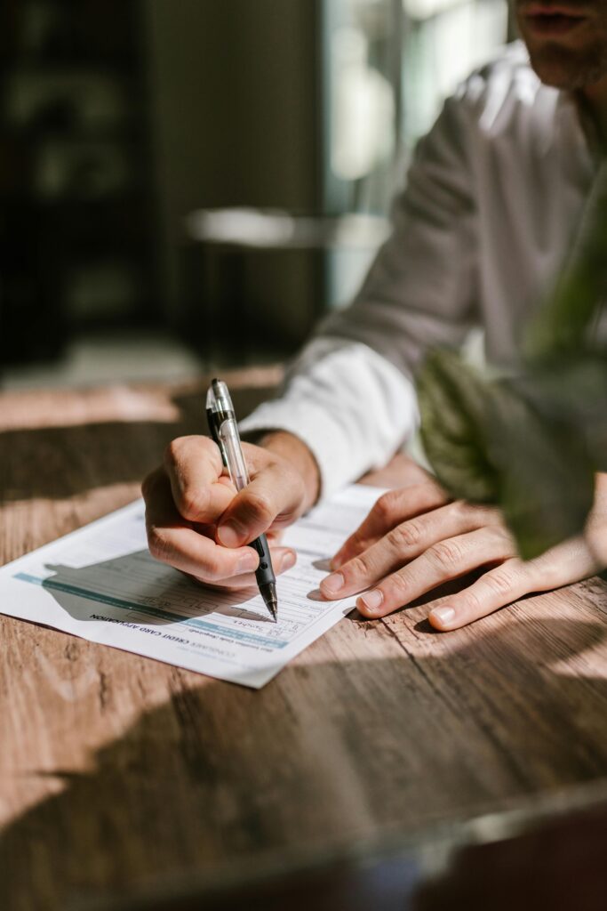 A professional filling out tax forms with a pen at a desk, captured in soft lighting.